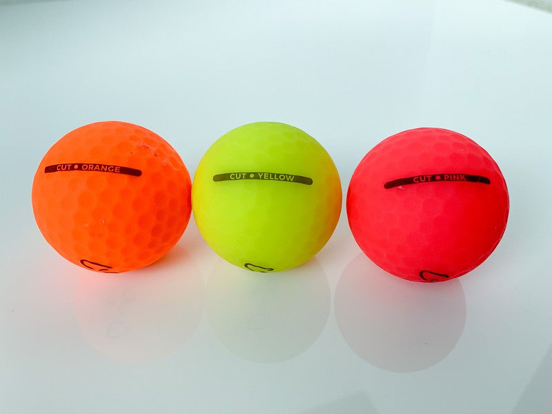 Three Matte Colored Golf Balls Lined Up