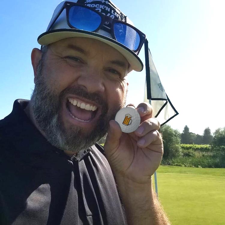 Golfer on the Green Holds a Beer Logo Golf Ball and Smiles