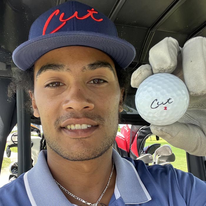 Golf Influencer Holding a Cut Blue Ball While Sitting in a Golf Cart