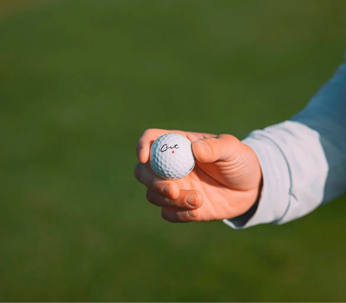 Golfer Holding Cut Grey Ball In Right Hand With Logo Showing