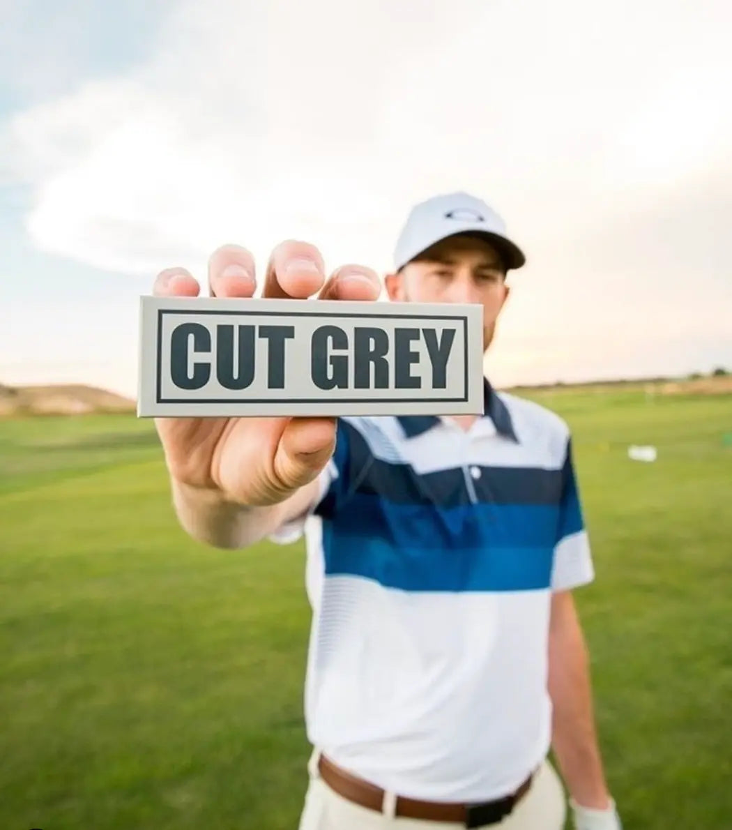 Golfer Holding a Sleeve of Cut Grey Balls In Front of Him