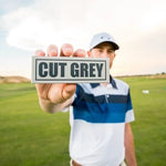 Golfer Holding a Sleeve of Cut Grey Balls In Front of Him